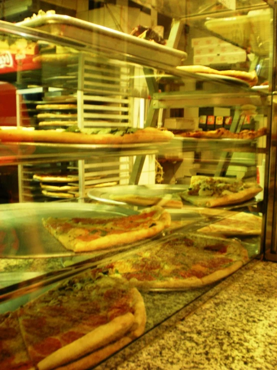 a bunch of pizzas are in a glass case