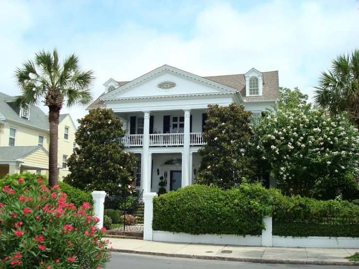 the front of a large home surrounded by palm trees