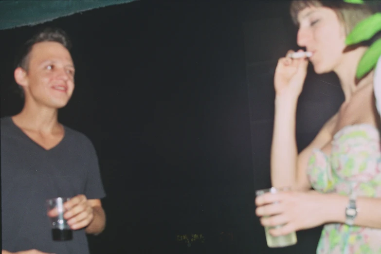 a man and woman sharing a piece of cake while drinking soda