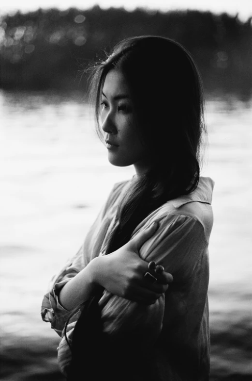 a woman standing by the water with her arms crossed