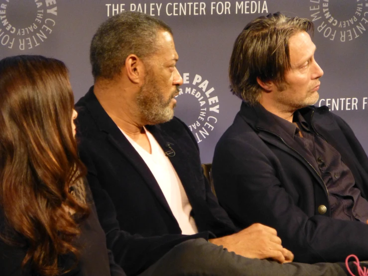 two men sitting next to each other on a red carpet