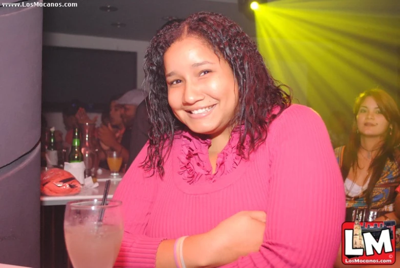 a woman posing for the camera with a beverage in hand