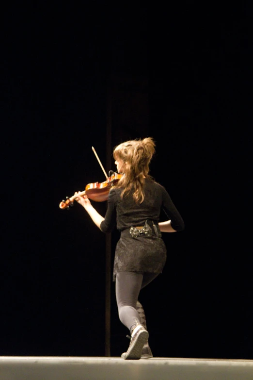 a woman is playing violin in a dark room