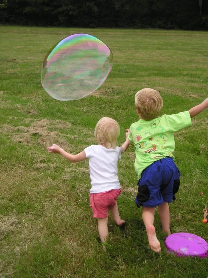 two young children with soap bubbles in a field