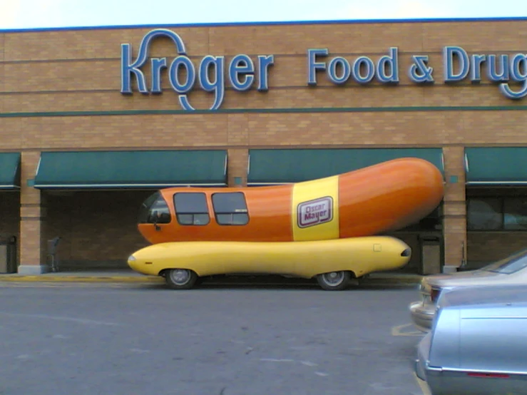 a large yellow and orange  dog inflatable vehicle in front of a burger restaurant
