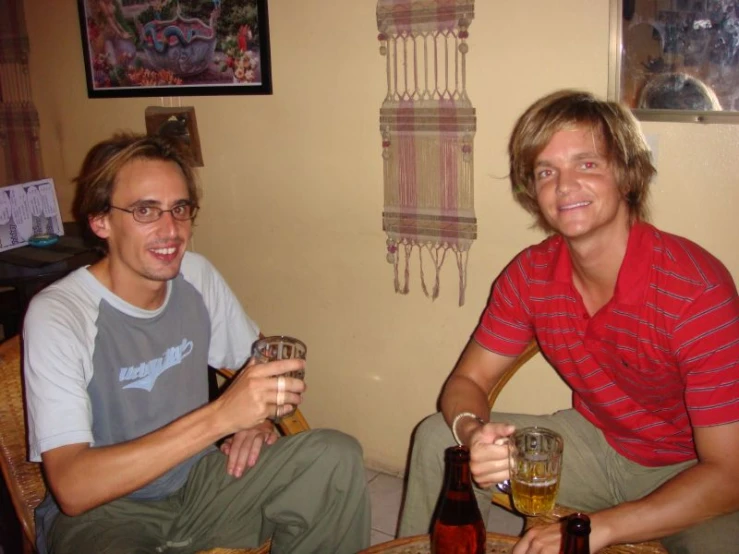 two men sitting on the floor drinking beer