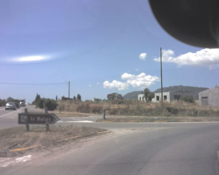 the view from the front seat of a vehicle on the road, looking out at an intersection