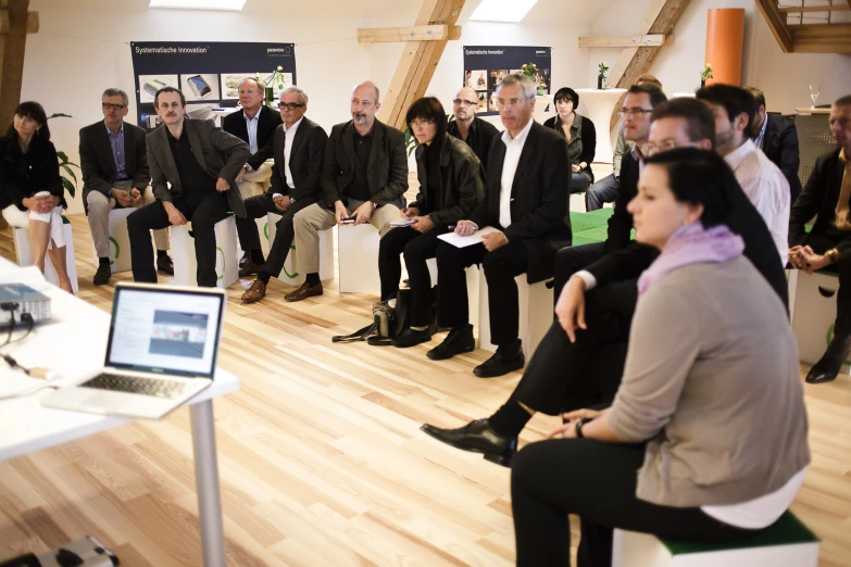 a crowd of people sitting on chairs in front of a screen