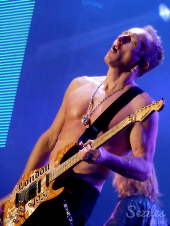 a man playing guitar while standing up on stage