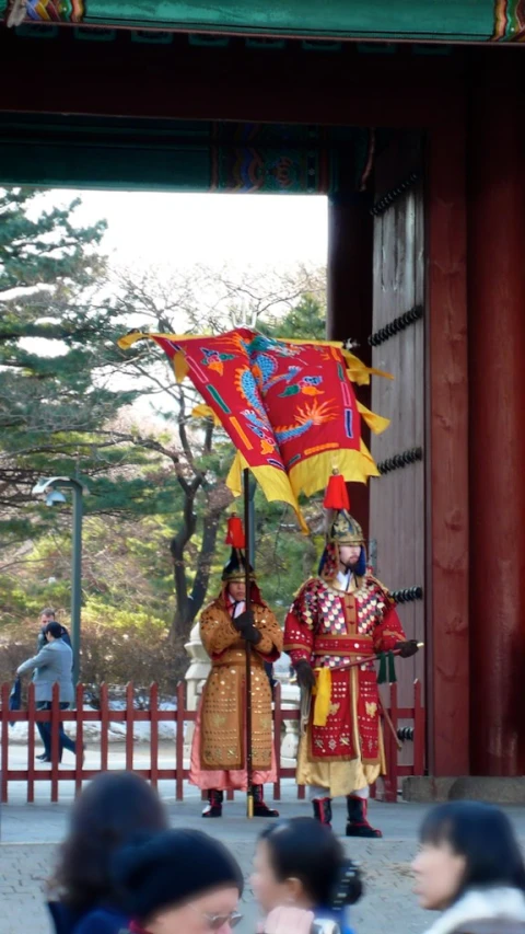 two people in costume stand in front of a red and gold building
