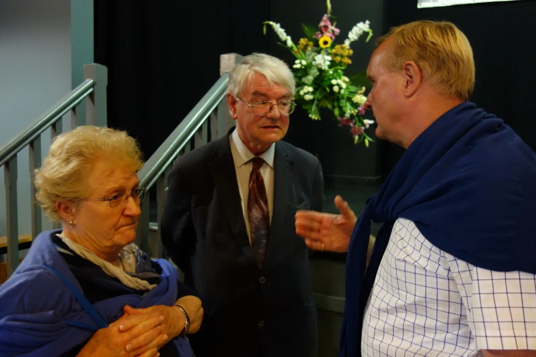 three older people stand in front of the stairs