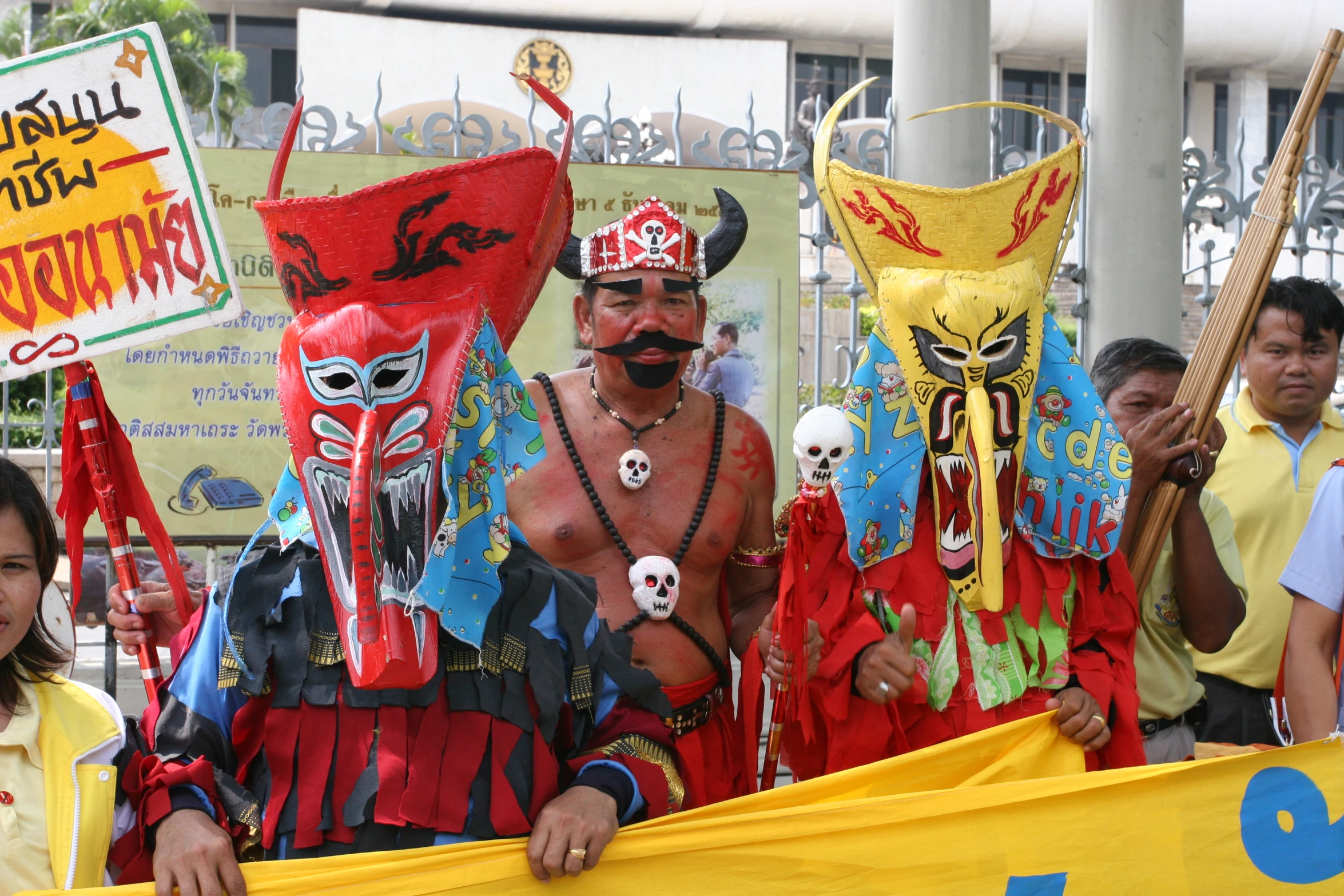 a man with large mustaches and costumes stands next to two women, wearing masks