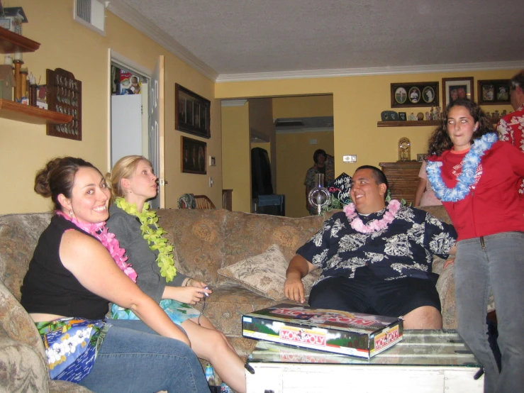 three people sitting on a couch and two of them are wearing leis