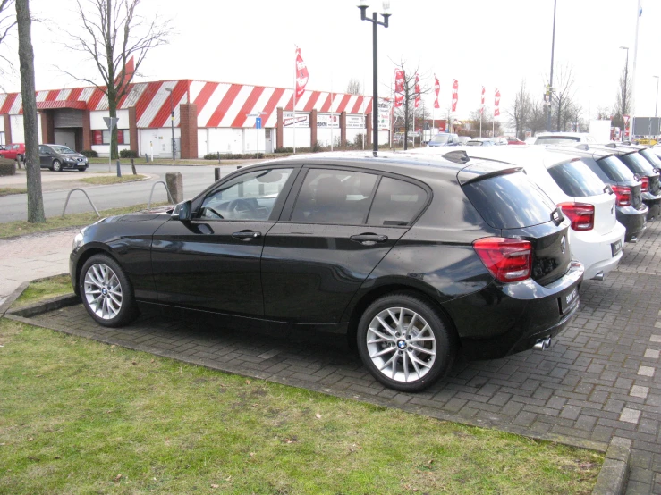 black bmw cars parked in a parking lot next to a brick walkway