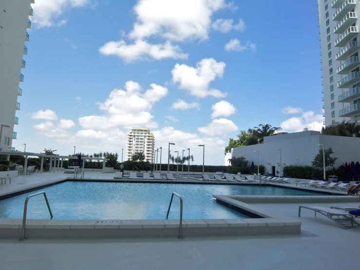 a large swimming pool sits in front of tall white buildings