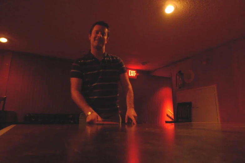 a man standing in a dark room next to a table