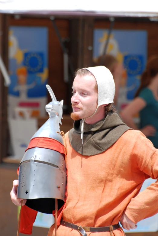 a man dressed in medieval clothing holds a silver vase