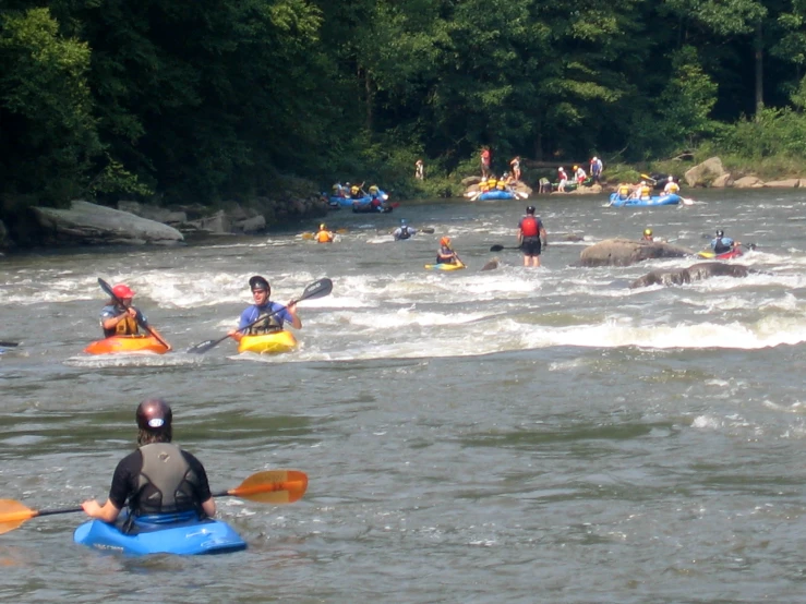 several people in kayaks paddling on river rapids