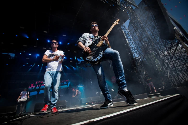 two young men playing guitars on stage at a concert