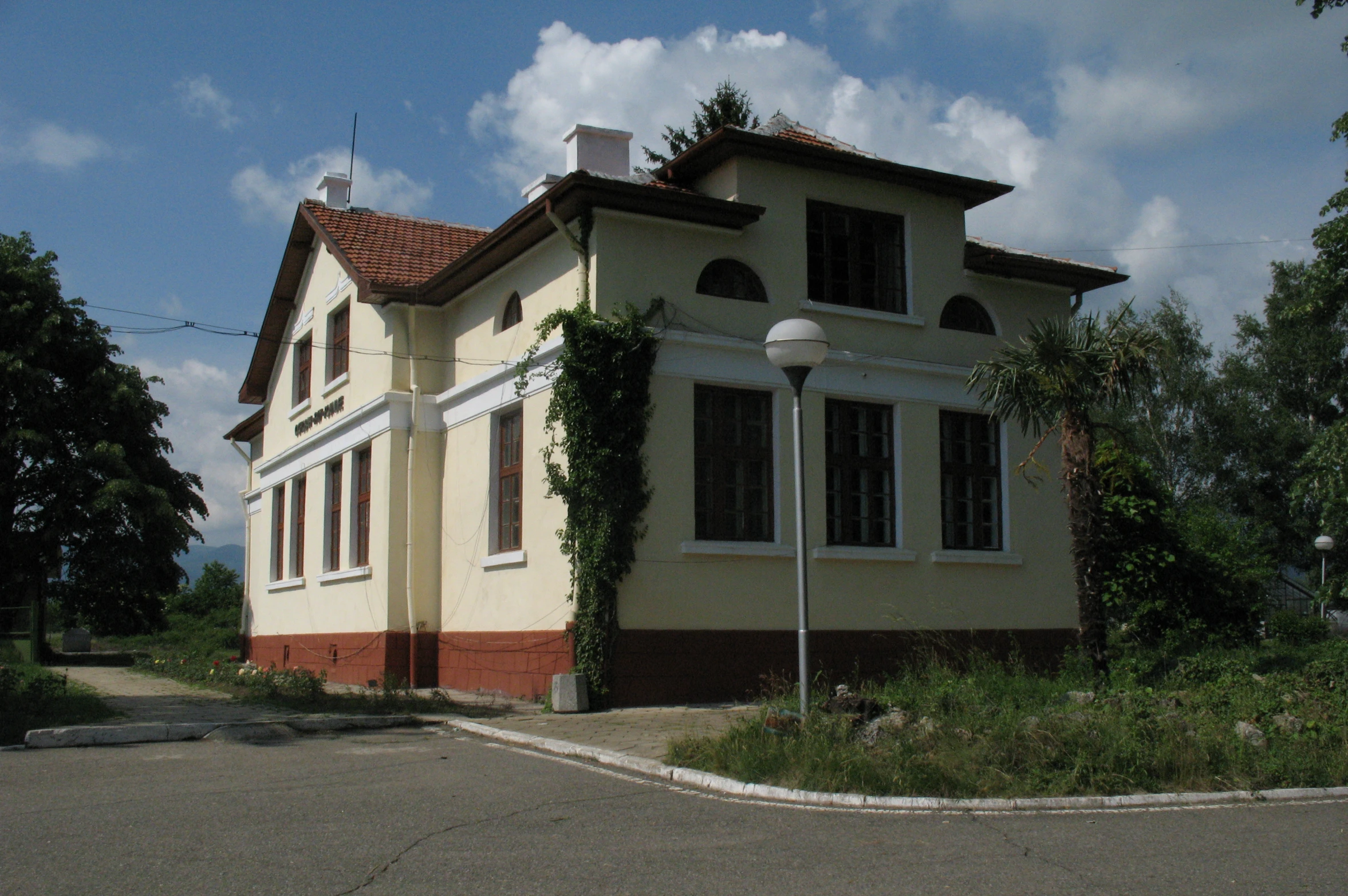 an old building with a lamp post and shrubs on it