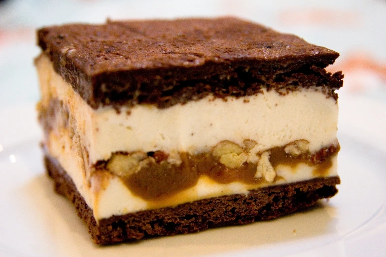 a piece of brownie with cream and chocolate on a white plate
