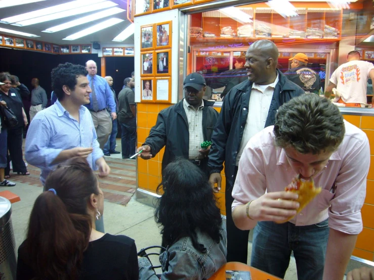 a person eating food as people stand around