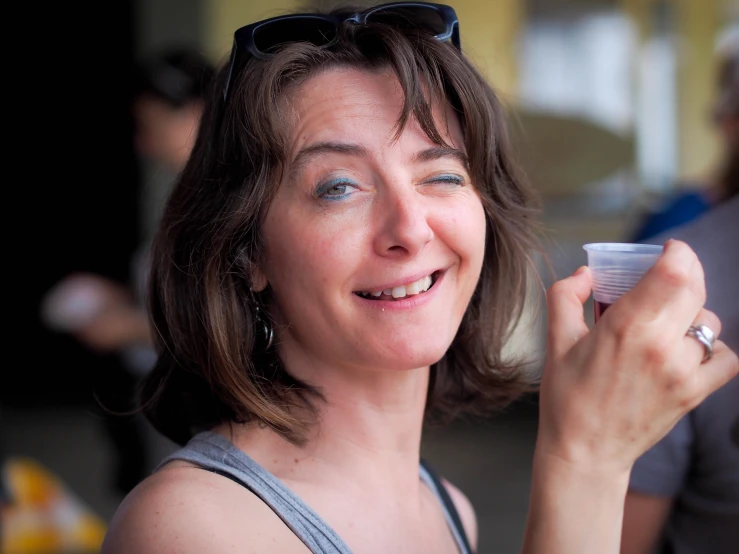 woman holding up a lip bale and smiling at the camera