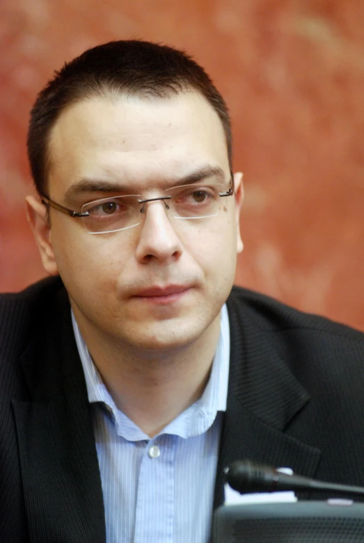 a man wearing glasses in front of a monitor