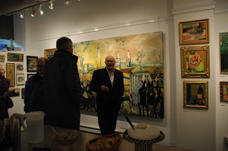 an old man in a business suit standing by paintings