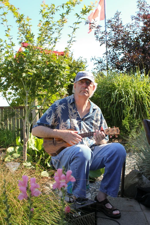 a man sitting outside playing a guitar