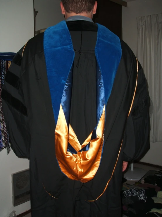 a man wearing a black and blue robe standing next to a closet