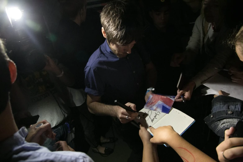 a man is surrounded by reporters using a cellphone