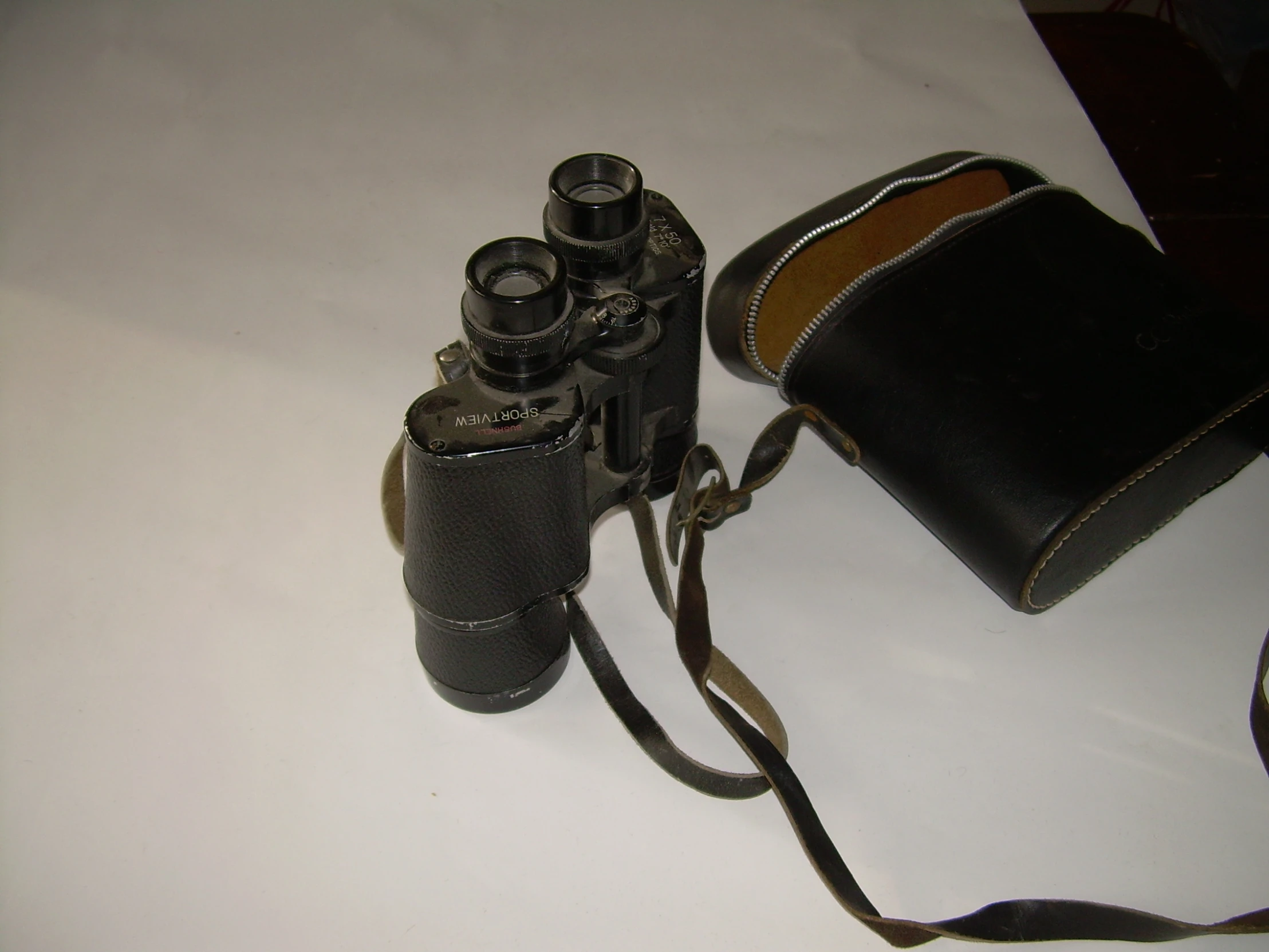 a leather camera case and two binoculars sitting on a table