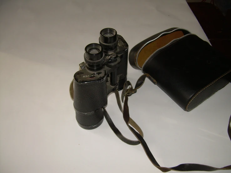 a leather camera case and two binoculars sitting on a table