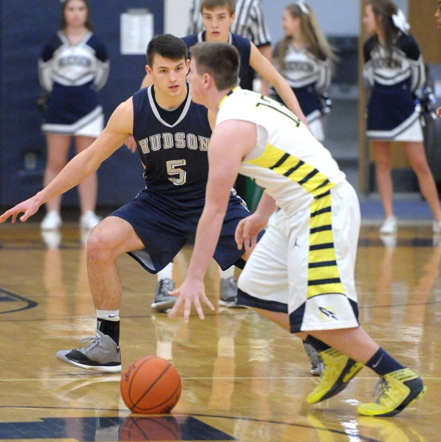 young men playing a game of basketball on a hard wood floor