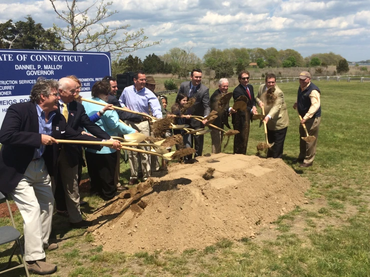 people stand outside with shovels and shovels in front of a mound of dirt