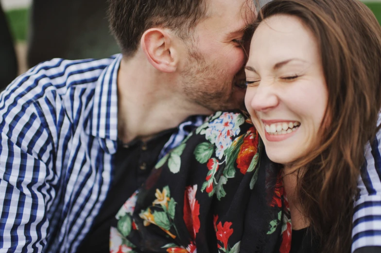 a man and a woman cuddle close together as they kiss