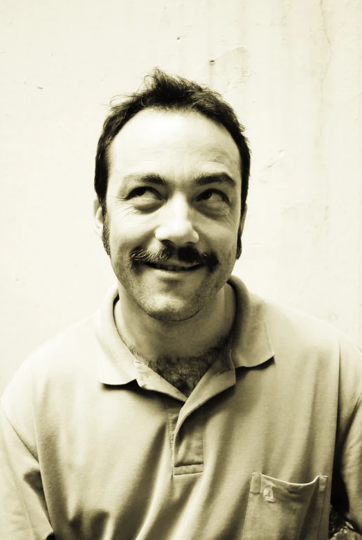 the man with beard smiles while wearing a shirt