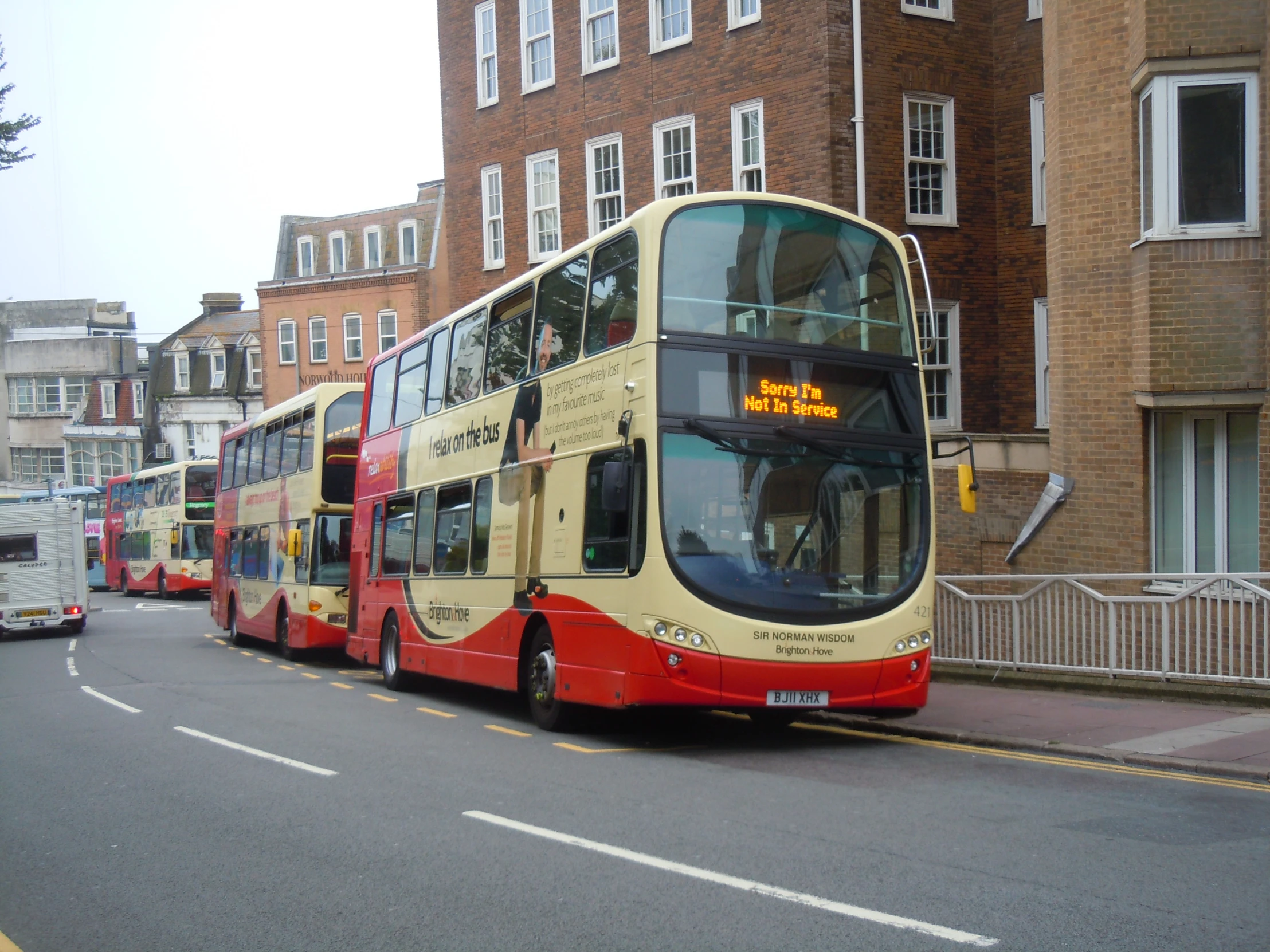 a couple of double decker buses sit parked by the curb