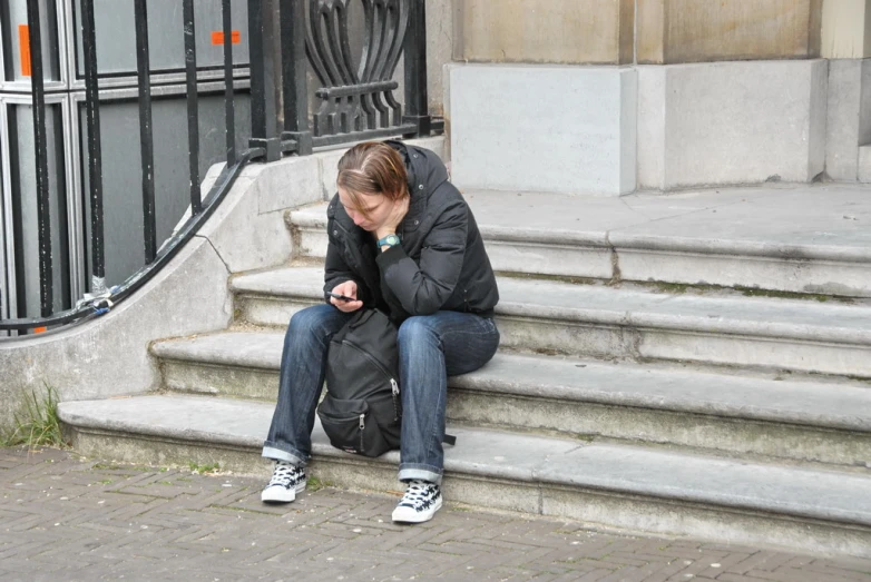 woman sitting on stairs checking her cell phone