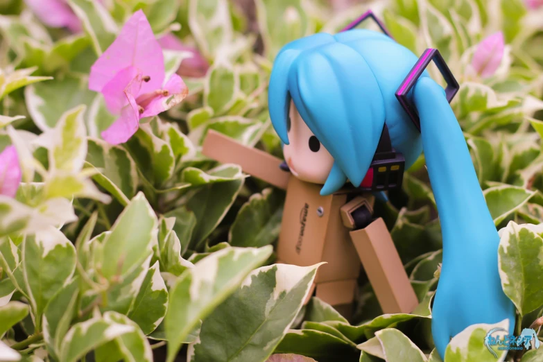 the doll sits in a field of pink flowers