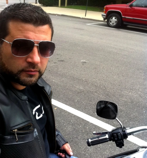 a man with sunglasses on standing next to his motorcycle