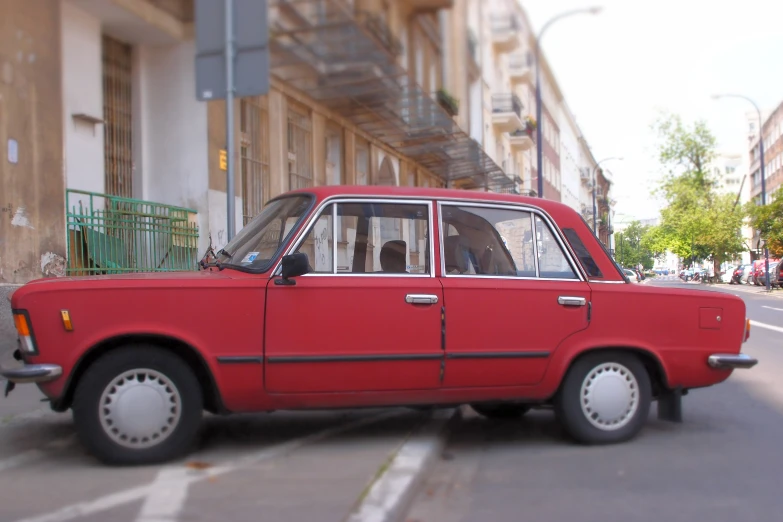 an old red car in the street with people riding in it