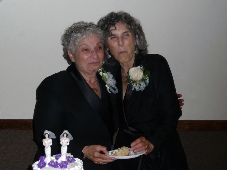 two women pose for a picture in front of a cake
