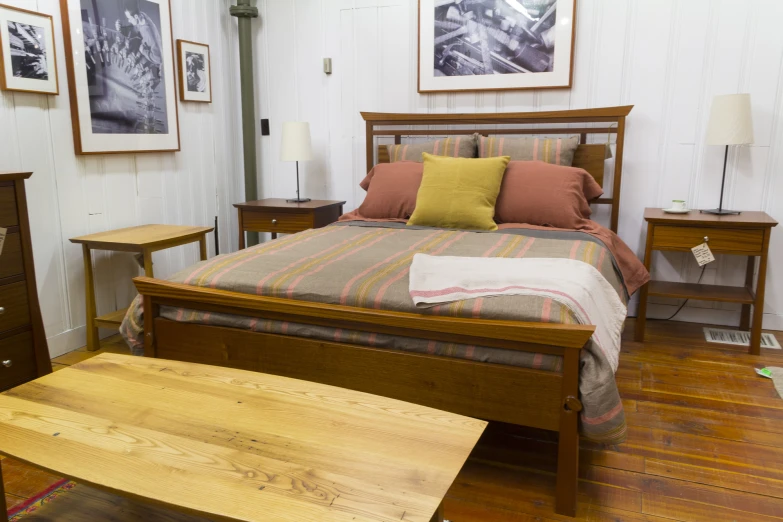 a wood - paneled bed with pillows, table and lamp