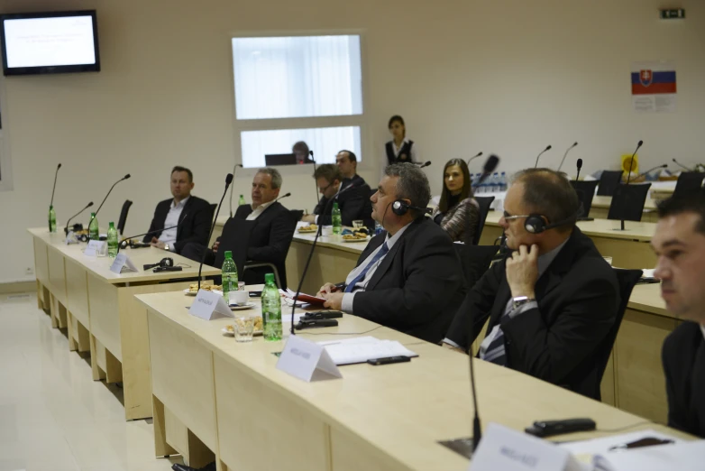 a group of men and women are sitting at their desks