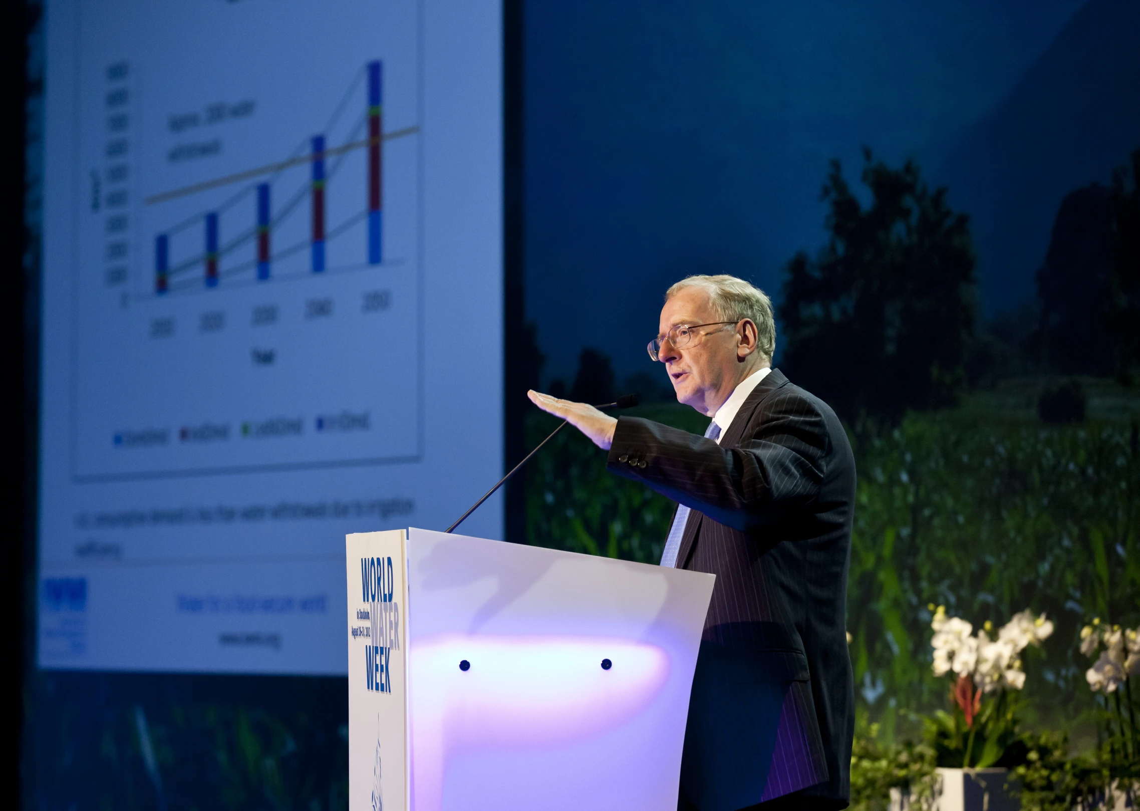 a man giving a speech on stage at a business seminar