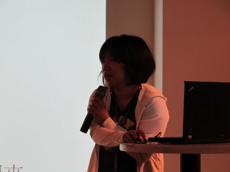 a woman stands at a podium speaking to people