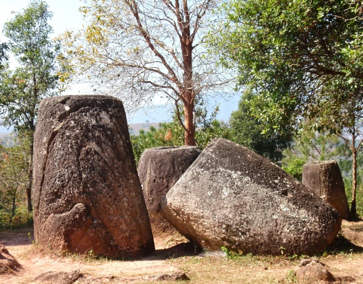 two large rocks in the dirt near some trees