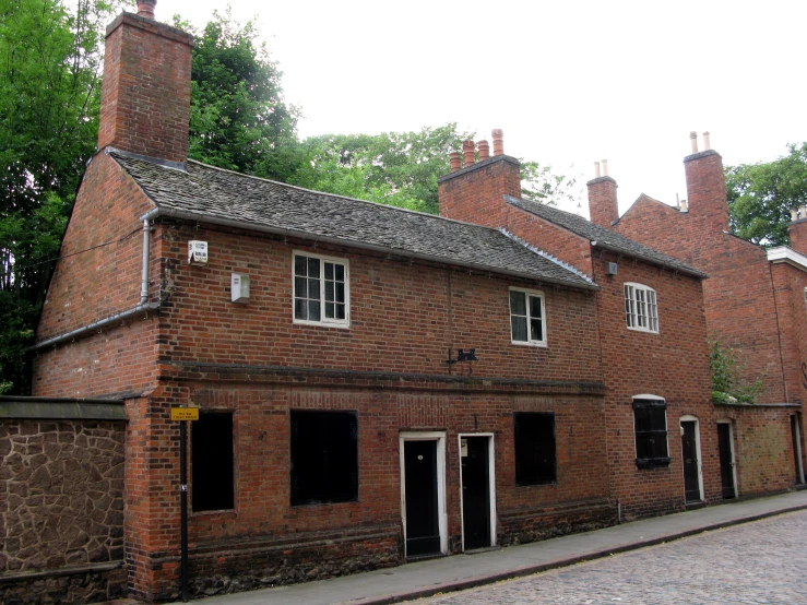 an old building with two brick chimneys near a sidewalk